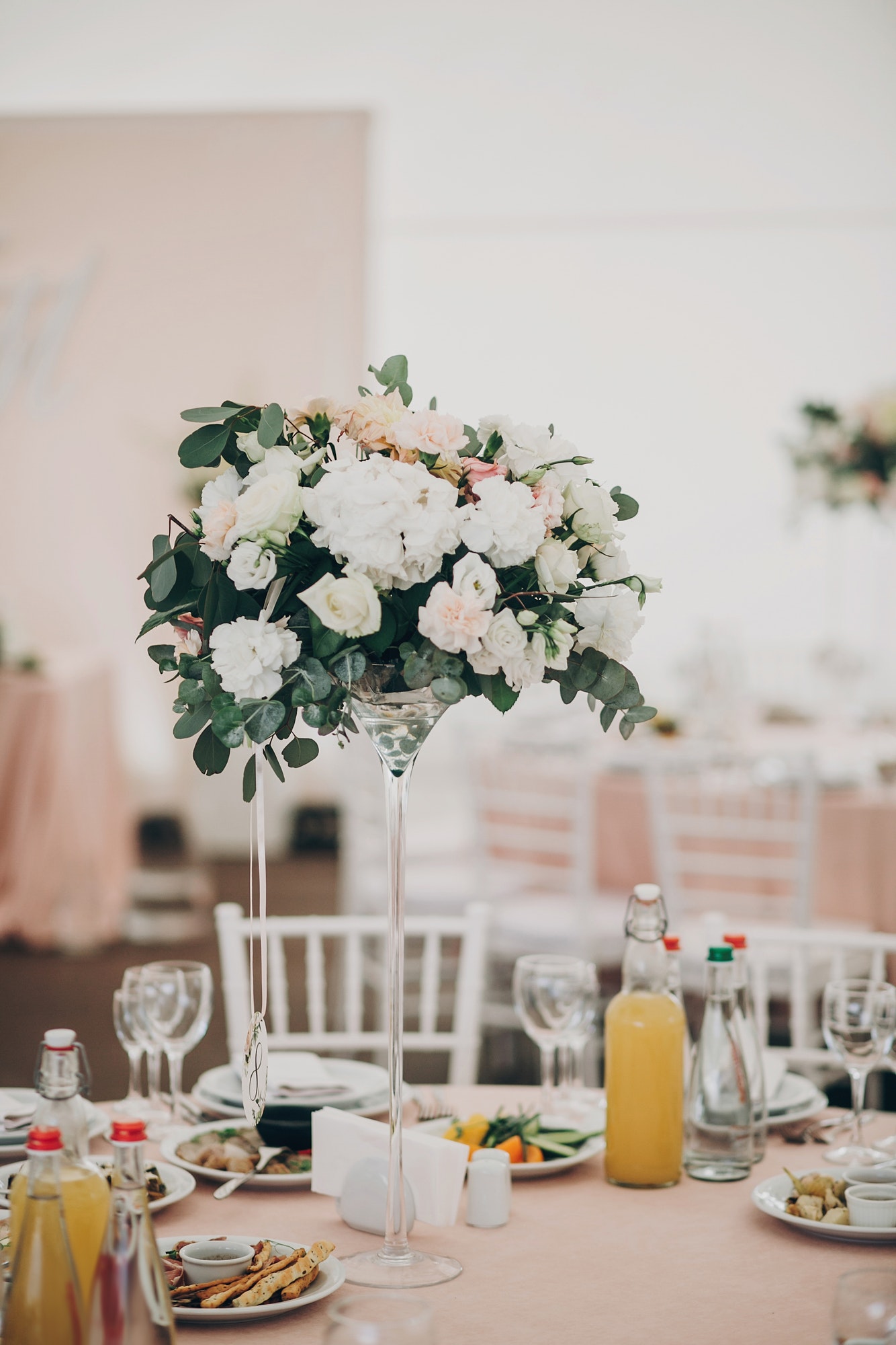 Wedding setting, tender pink table with glasses, cutlery, napkin and delicious food and drinks